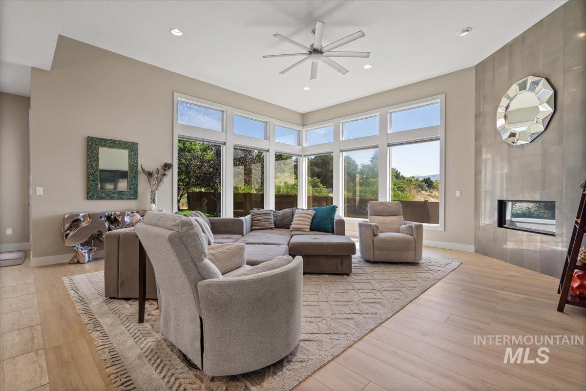 Living area featuring a ceiling fan, plenty of natural light, light wood-style floors, recessed lighting, and a high ceiling