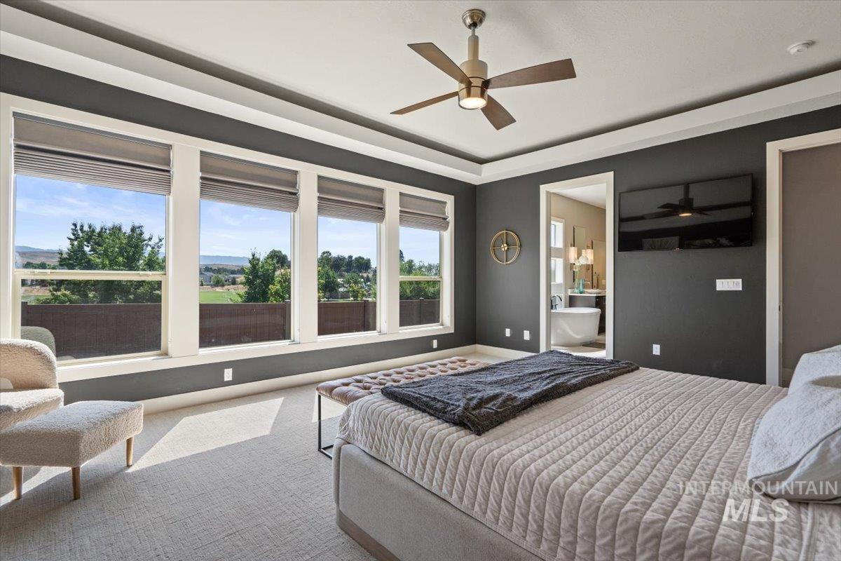 Carpeted bedroom featuring ensuite bath and ceiling fan