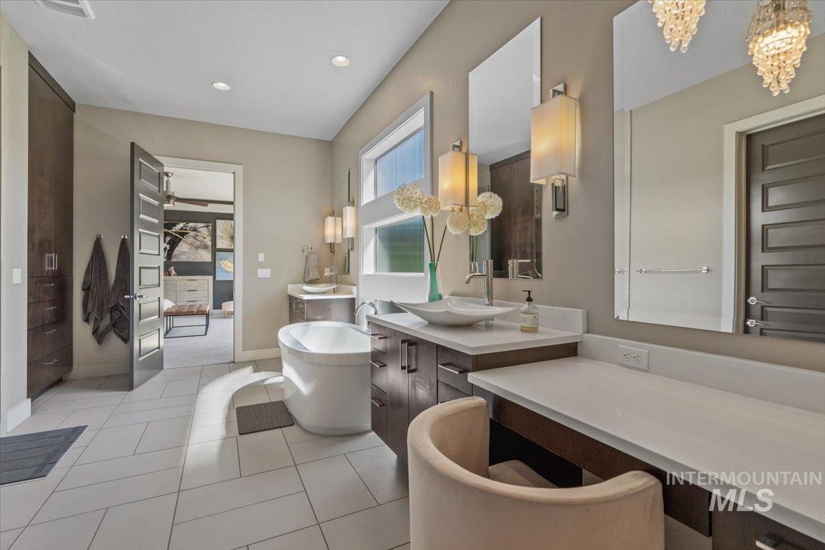 Bathroom featuring a freestanding bath, vanity, a chandelier, recessed lighting, and tile patterned flooring