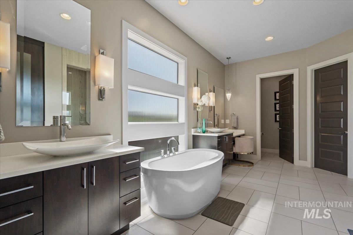 Full bathroom with two vanities, a soaking tub, recessed lighting, and tile patterned flooring