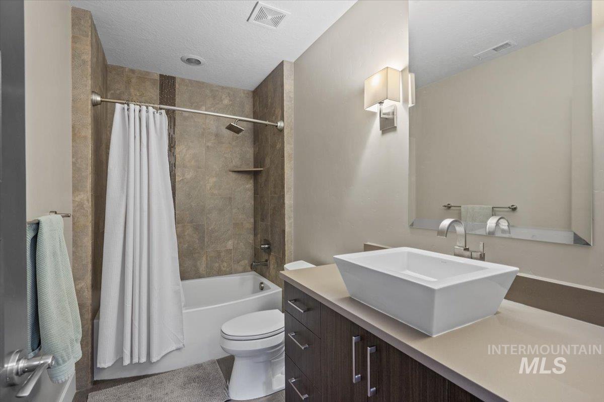 Full bath with shower / bath combo, vanity, and a textured ceiling