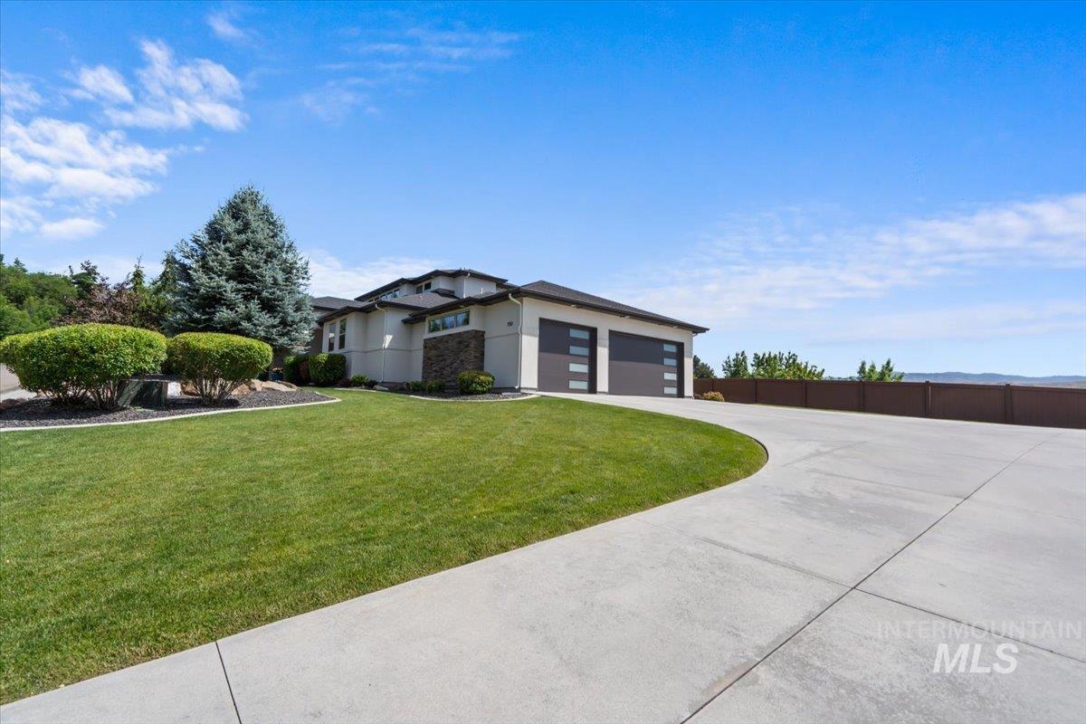 View of front of home with an attached garage, driveway, and stucco siding