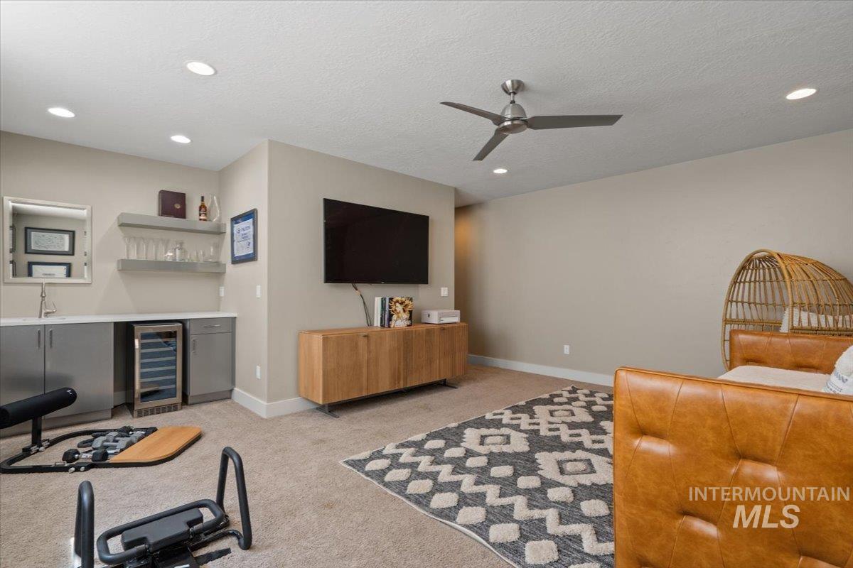 Living room with beverage cooler, a dry bar, a ceiling fan, light carpet, and recessed lighting