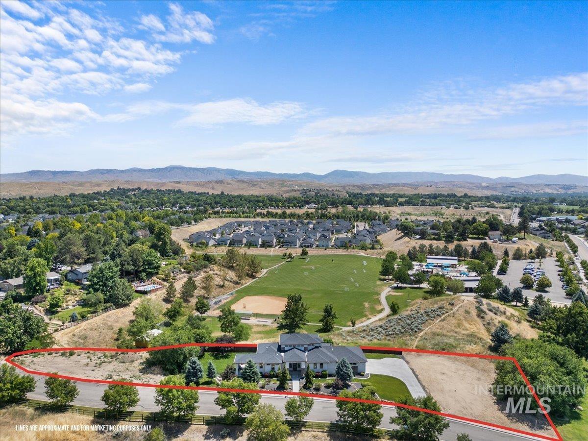 Aerial perspective of suburban area featuring property boundaries highlighted and a mountain backdrop