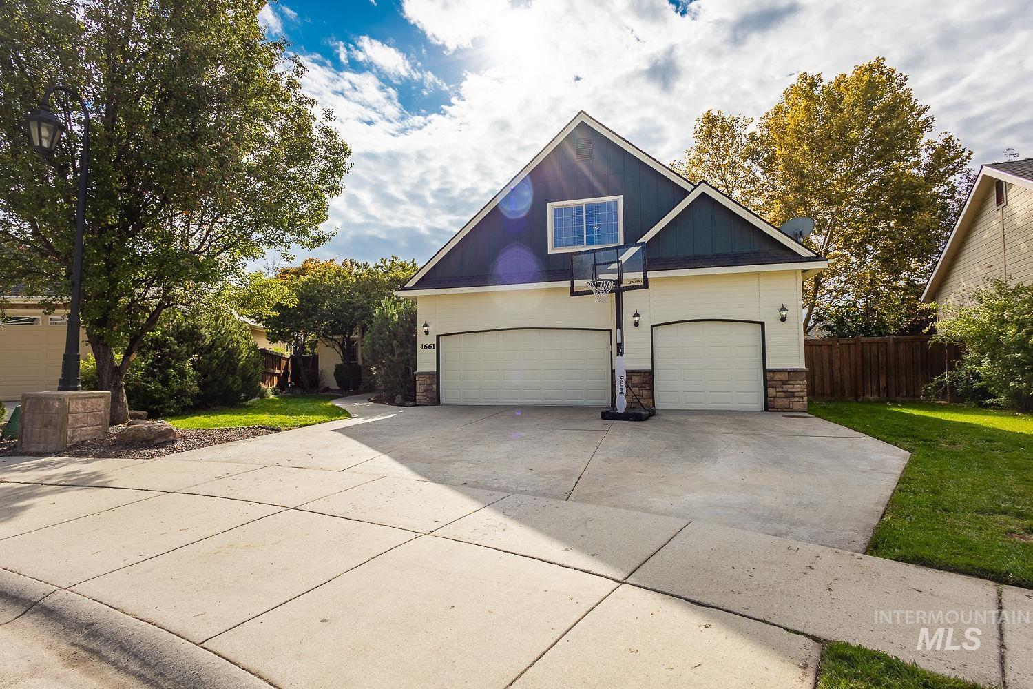 View of front of house featuring stone siding, driveway, and a garage