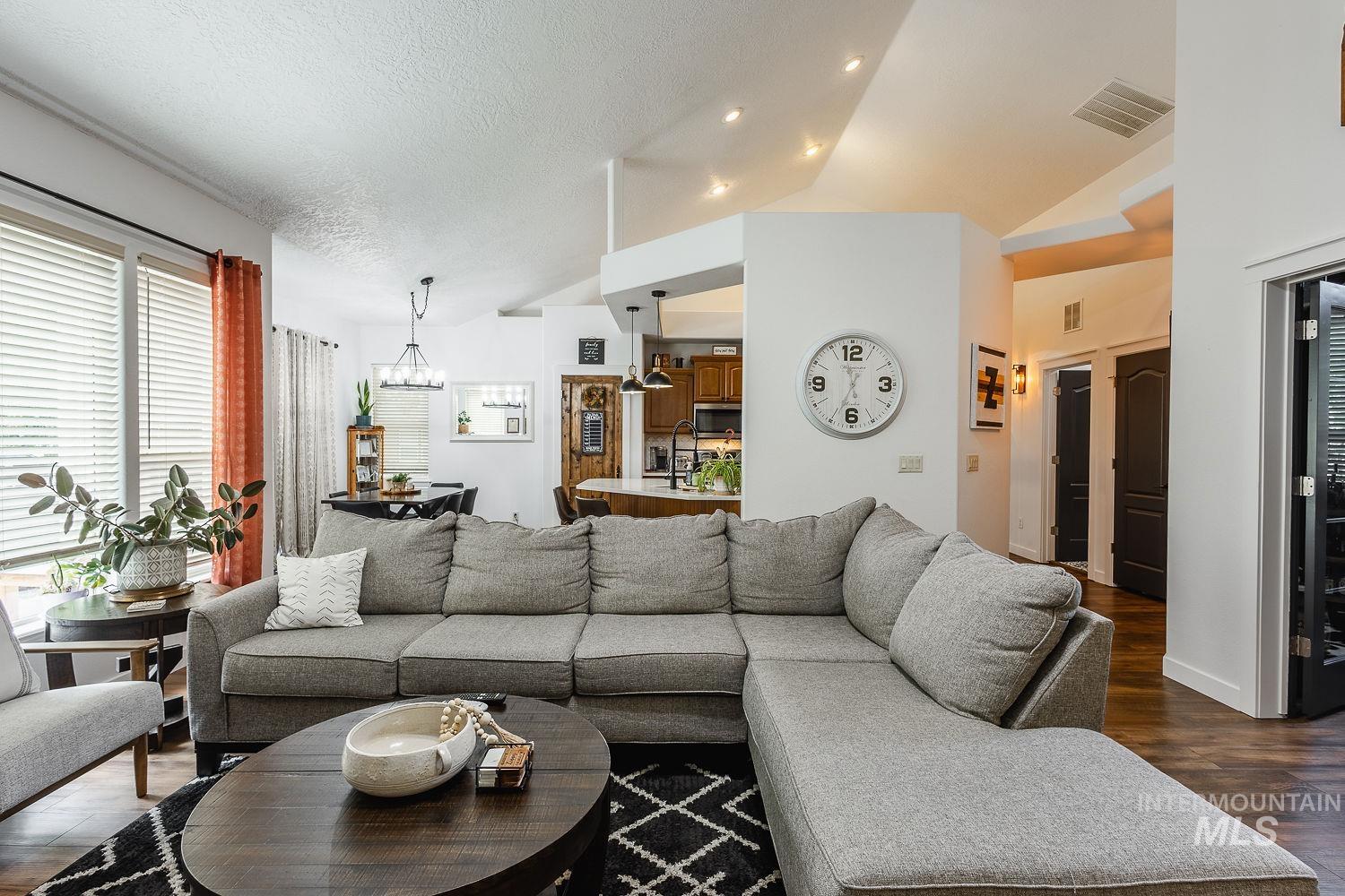 Living room featuring dark wood-style floors, vaulted ceiling, and a textured ceiling