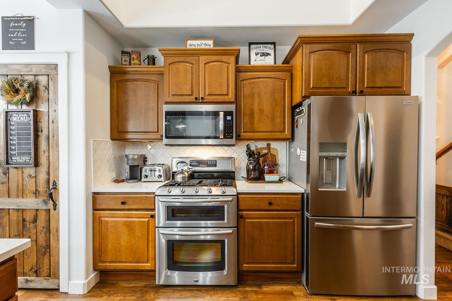 Kitchen featuring appliances with stainless steel finishes, backsplash, and brown cabinets