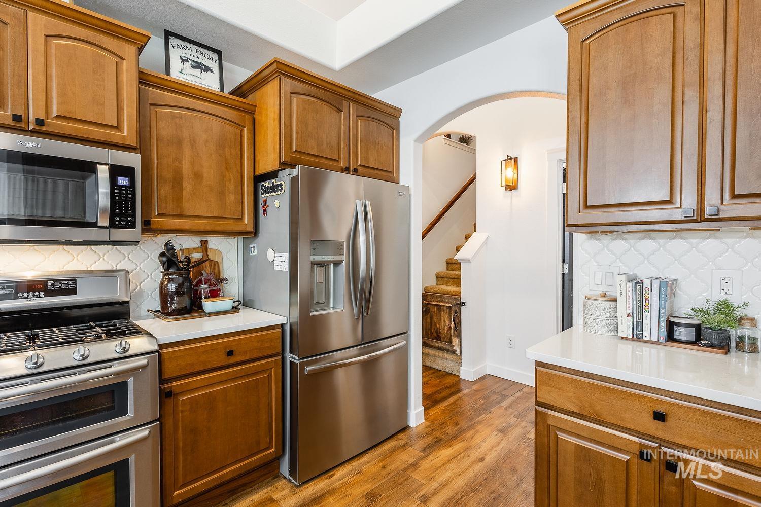 Kitchen featuring backsplash, appliances with stainless steel finishes, and brown cabinetry
