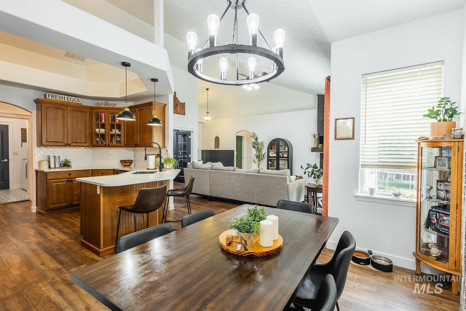 Dining room featuring arched walkways, dark wood-style flooring, vaulted ceiling, and a chandelier
