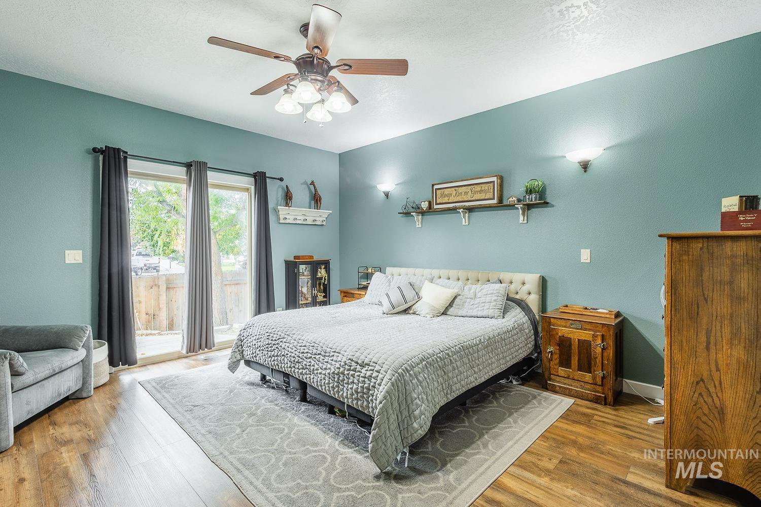 Bedroom featuring access to exterior, wood finished floors, ceiling fan, and a textured ceiling