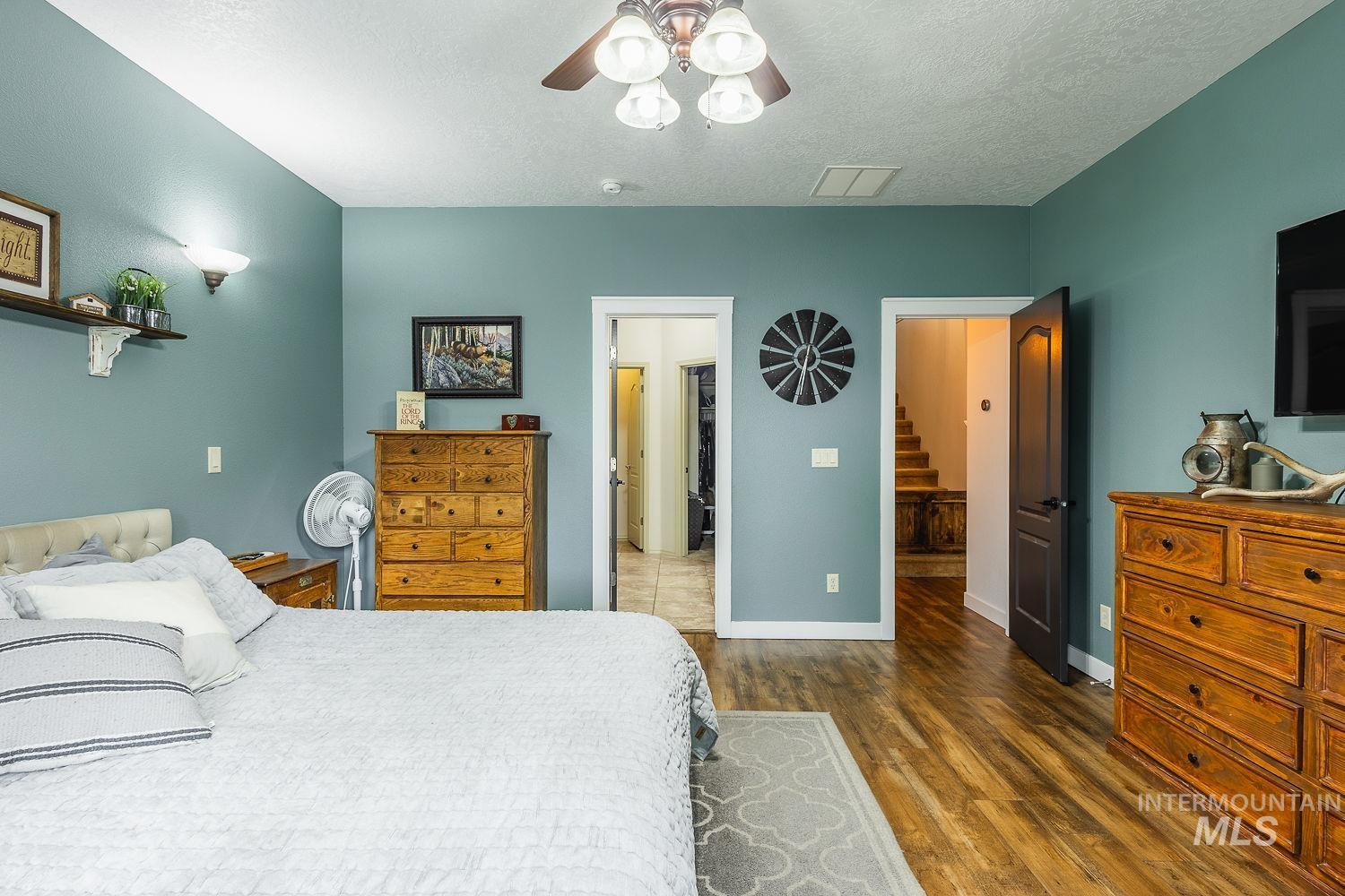 Bedroom with dark wood-style floors, a textured ceiling, ceiling fan, and connected bathroom