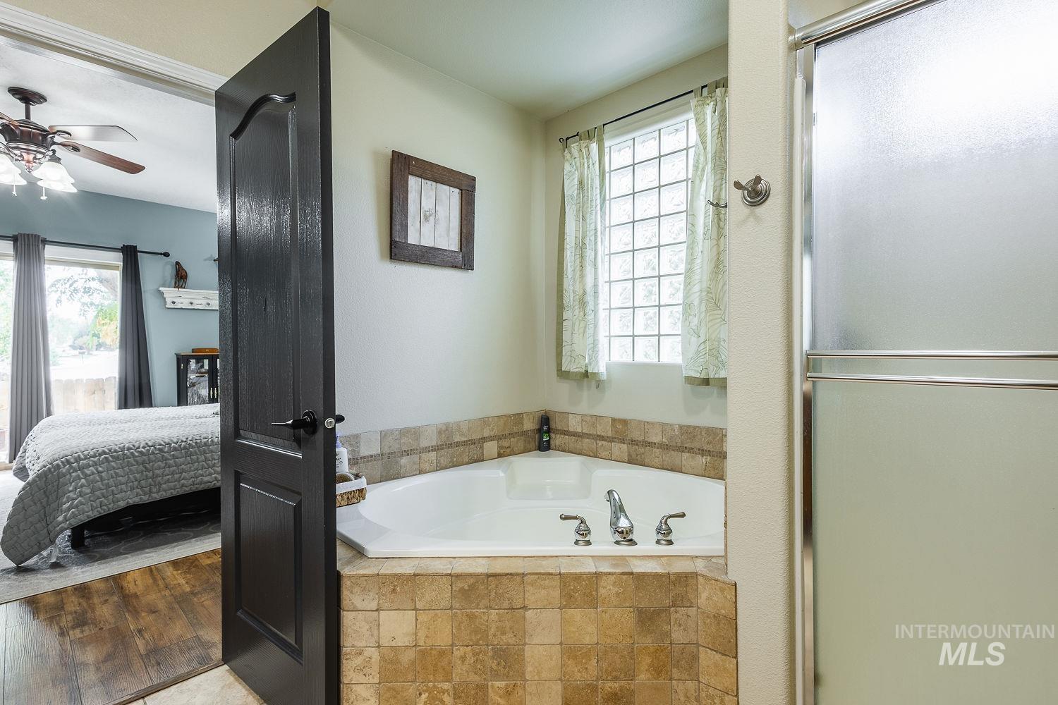 Bathroom featuring ensuite bathroom, a garden tub, and a shower stall