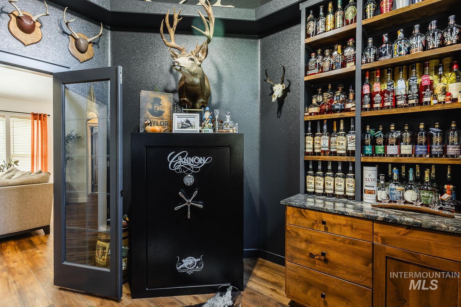 Bar featuring dark wood finished floors, dark stone counters, and brown cabinetry