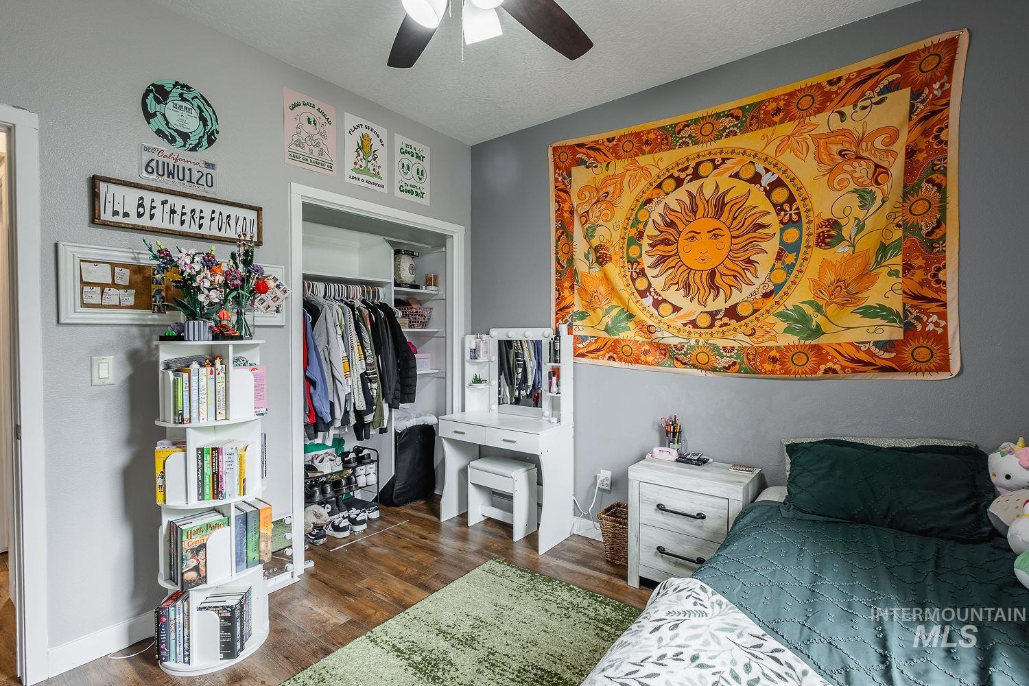 Bedroom featuring dark wood-style flooring, a textured ceiling, a closet, and ceiling fan