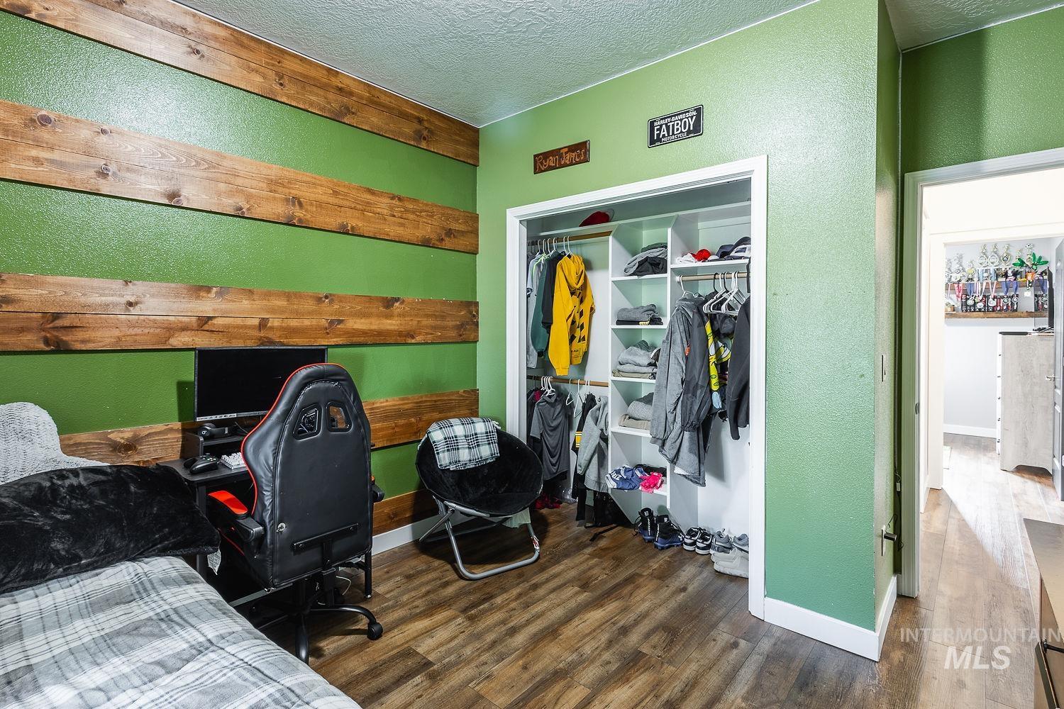 Bedroom featuring dark wood-style floors, a textured ceiling, a textured wall, and a closet