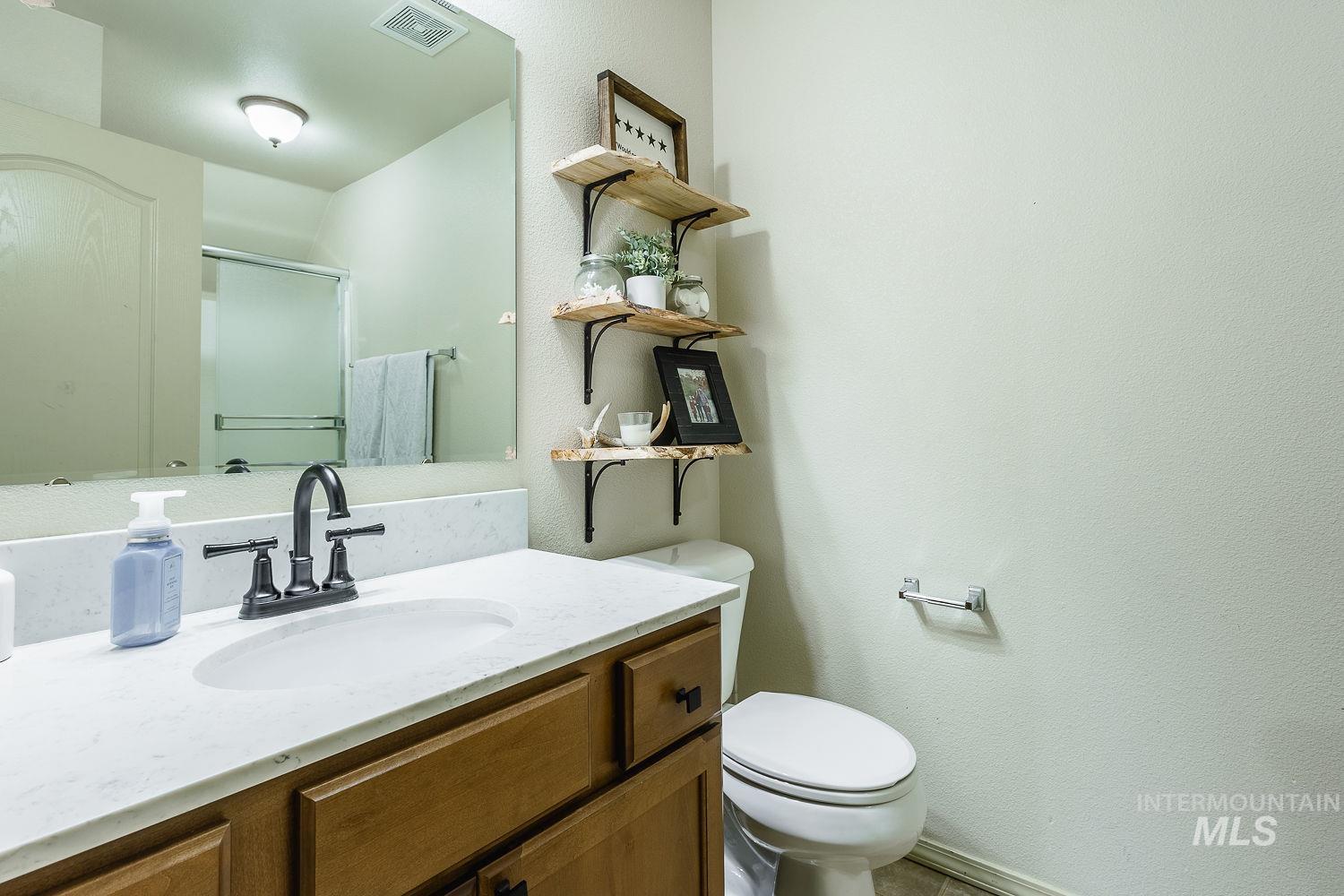 Full bath featuring a stall shower, vanity, and a textured wall