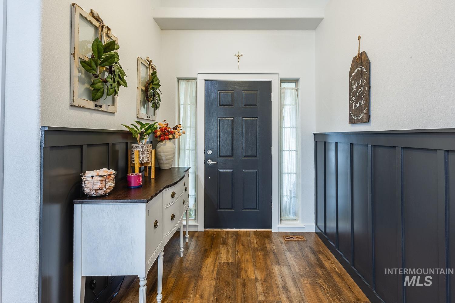Foyer with dark wood-style floors and a decorative wall