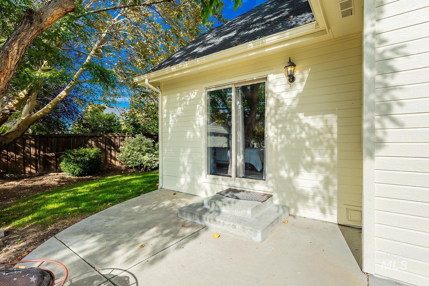 Doorway to property featuring a shingled roof and a patio