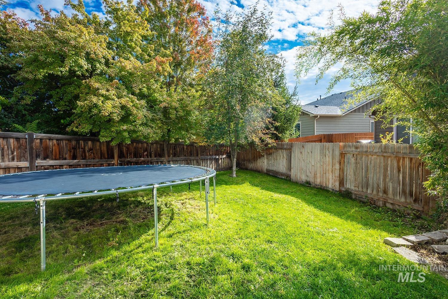 Fenced backyard featuring a trampoline