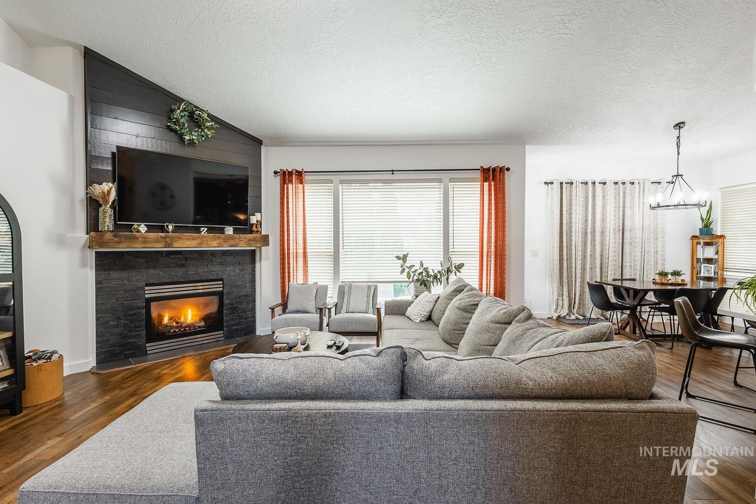 Living area featuring a textured ceiling, a chandelier, dark wood-type flooring, lofted ceiling, and a fireplace