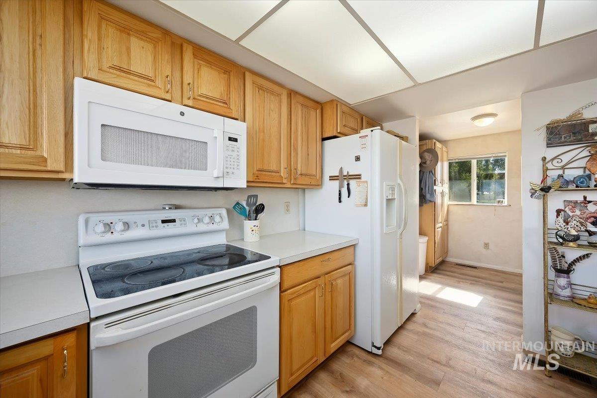 Kitchen with white appliances, light countertops, and light wood-style flooring