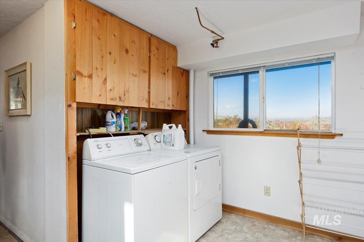 Laundry room with washing machine and dryer and a textured ceiling