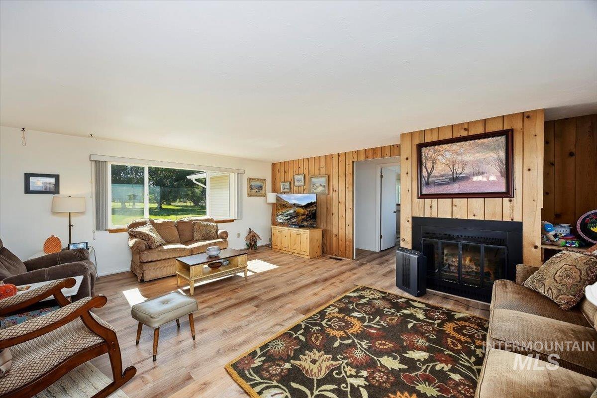 Living room featuring wood finished floors, wooden walls, and a glass covered fireplace
