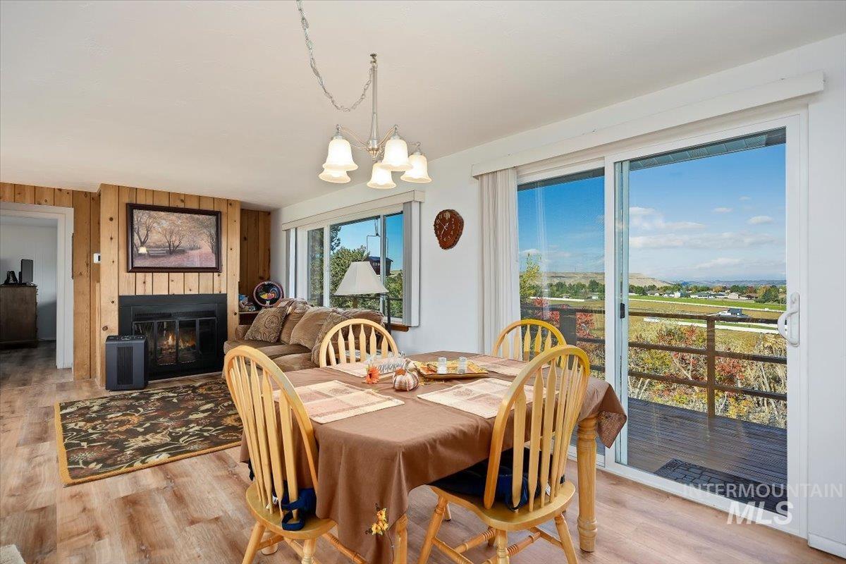 Dining space featuring wood walls, light wood finished floors, a chandelier, and a glass covered fireplace