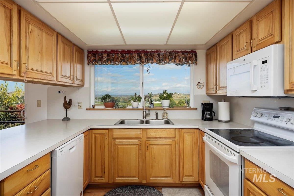 Kitchen with white appliances, light countertops, and brown cabinets