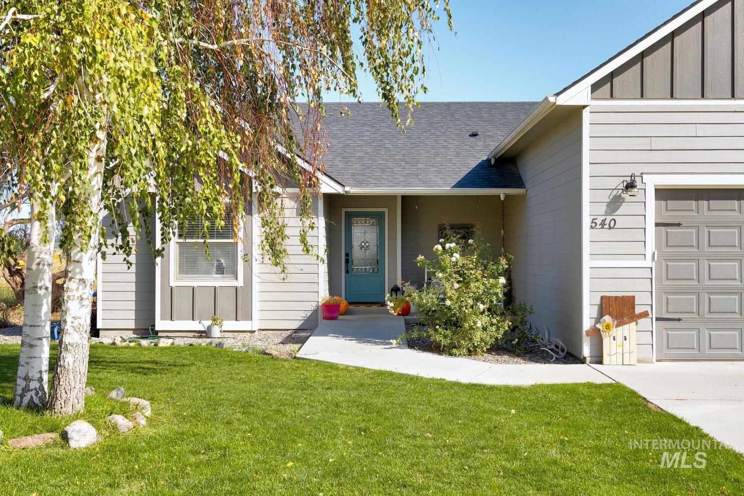 Property entrance featuring a shingled roof, a lawn, an attached garage, and board and batten siding