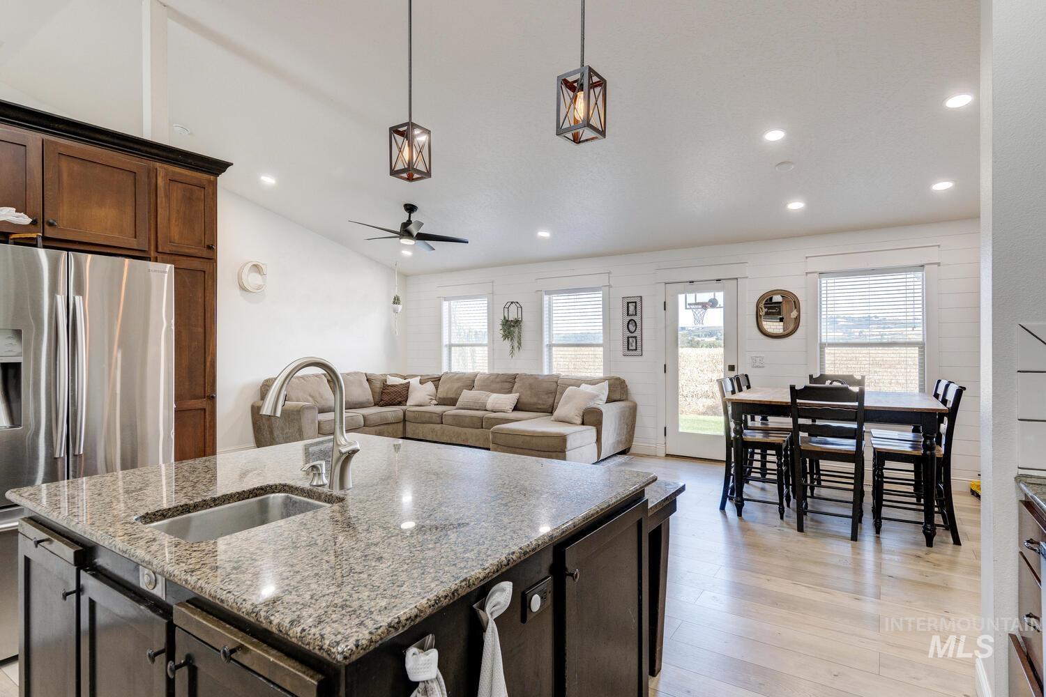 Kitchen with dark brown cabinets, recessed lighting, decorative light fixtures, light wood-type flooring, and stainless steel refrigerator with ice dispenser