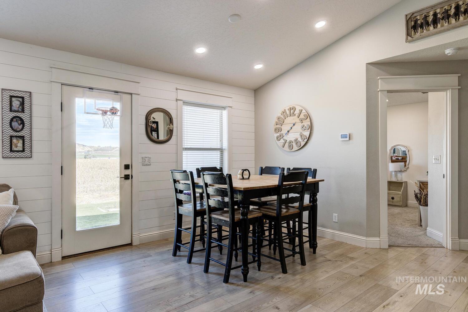 Dining room with plenty of natural light, vaulted ceiling, light wood-style floors, recessed lighting, and wood walls