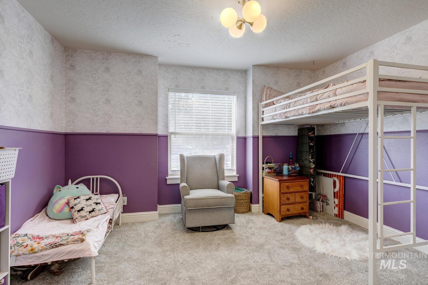 Bedroom with light carpet, a textured ceiling, and wallpapered walls
