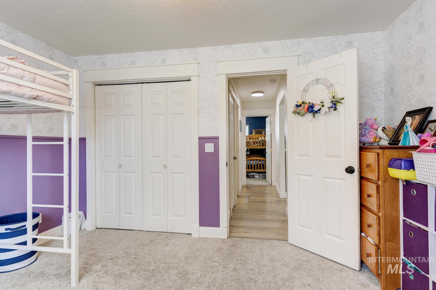 Bedroom with light carpet, a textured ceiling, and a closet
