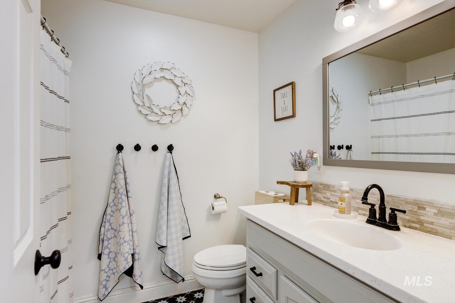 Bathroom with decorative backsplash, a shower with shower curtain, vanity, and tile patterned flooring