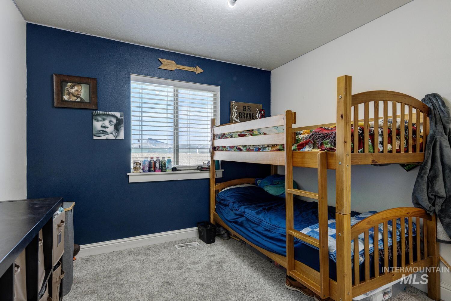 Bedroom with light colored carpet and a textured ceiling