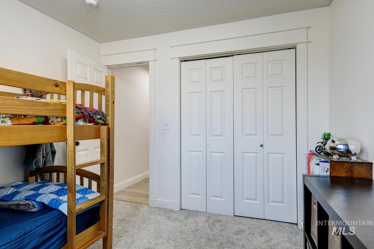 Bedroom with light carpet, a closet, and a textured ceiling