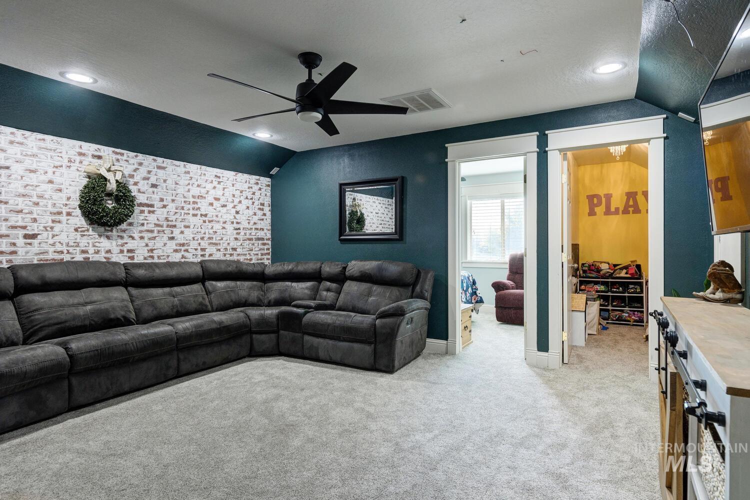 Living area with lofted ceiling, carpet floors, an accent wall, a ceiling fan, and recessed lighting