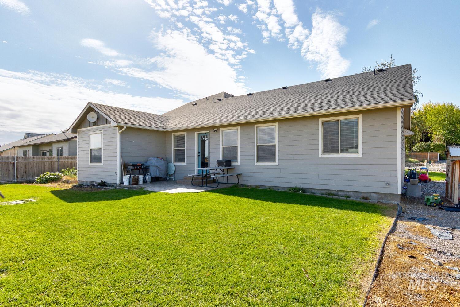 Back of property with roof with shingles and a patio area