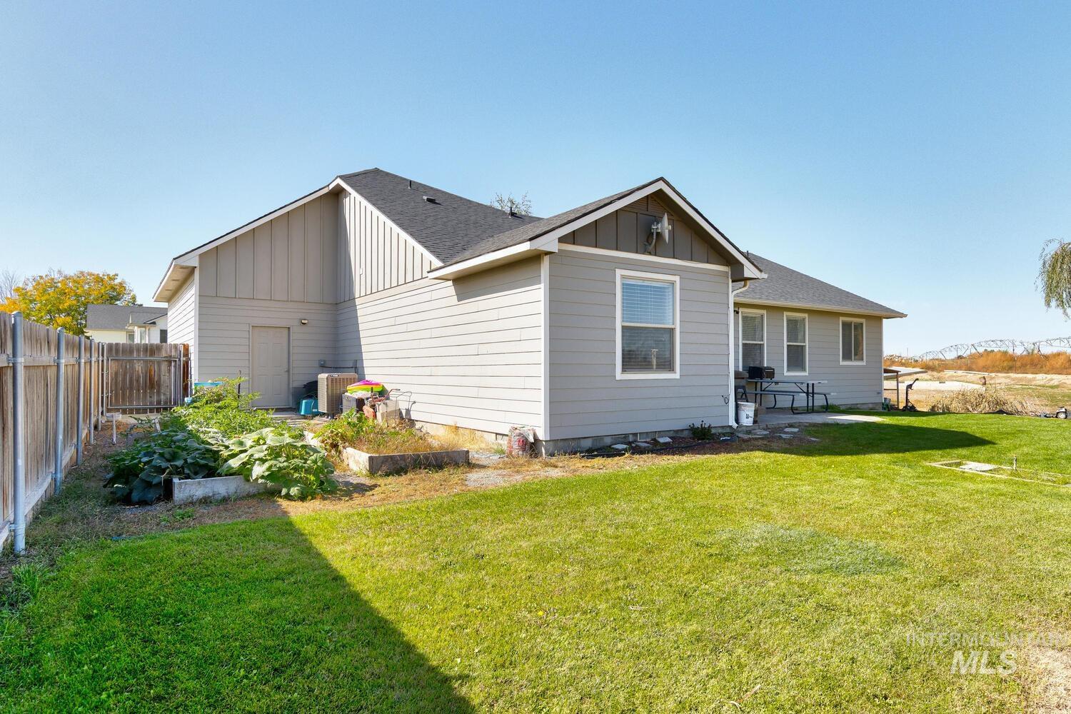 Rear view of house with board and batten siding, a shingled roof, a patio, and a garden