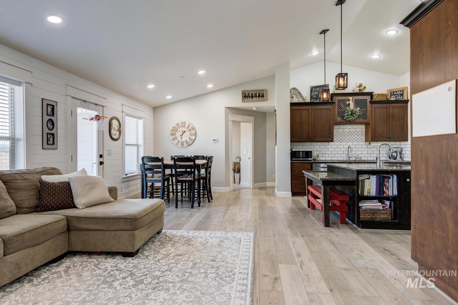 Living room featuring vaulted ceiling, light wood-style flooring, and recessed lighting