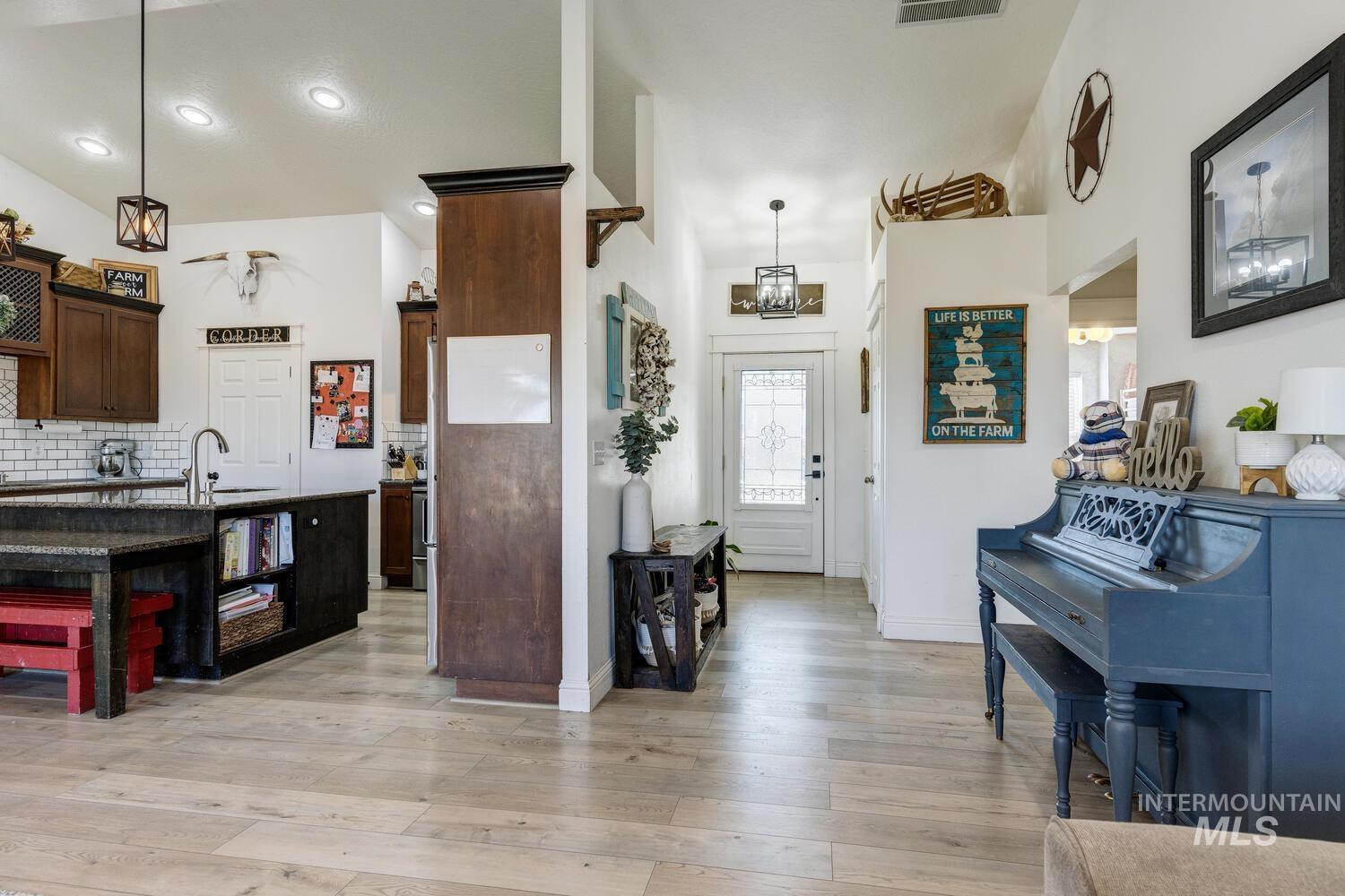 Kitchen featuring decorative backsplash, light wood-style flooring, decorative light fixtures, dark brown cabinetry, and dark stone counters