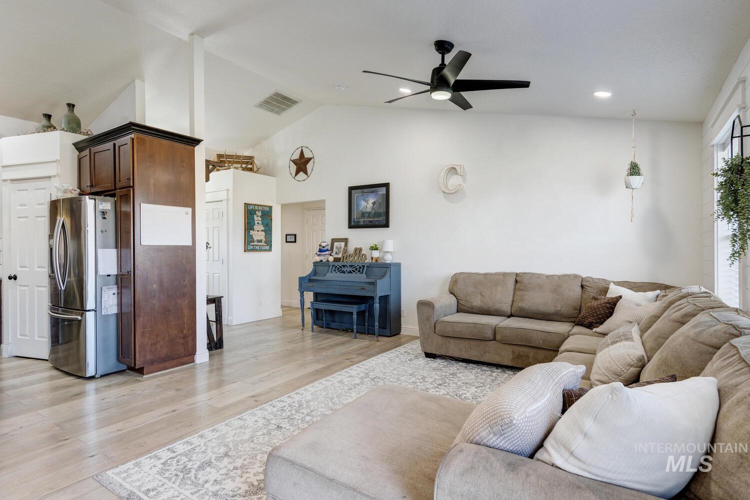 Living area featuring lofted ceiling, light wood-type flooring, a ceiling fan, and recessed lighting