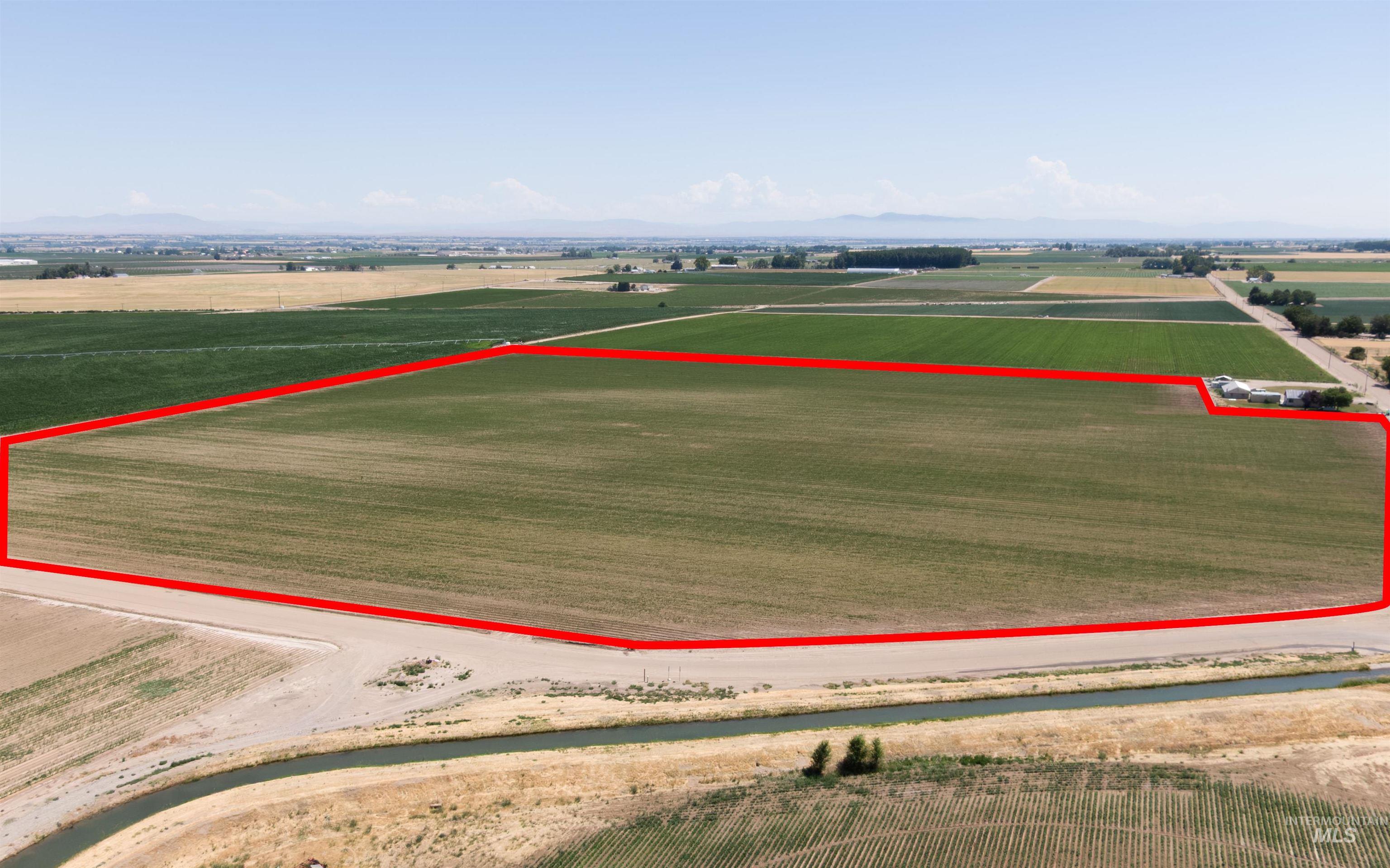 Aerial view of sparsely populated area with extensive farmland, property parcel outlined, and mountains