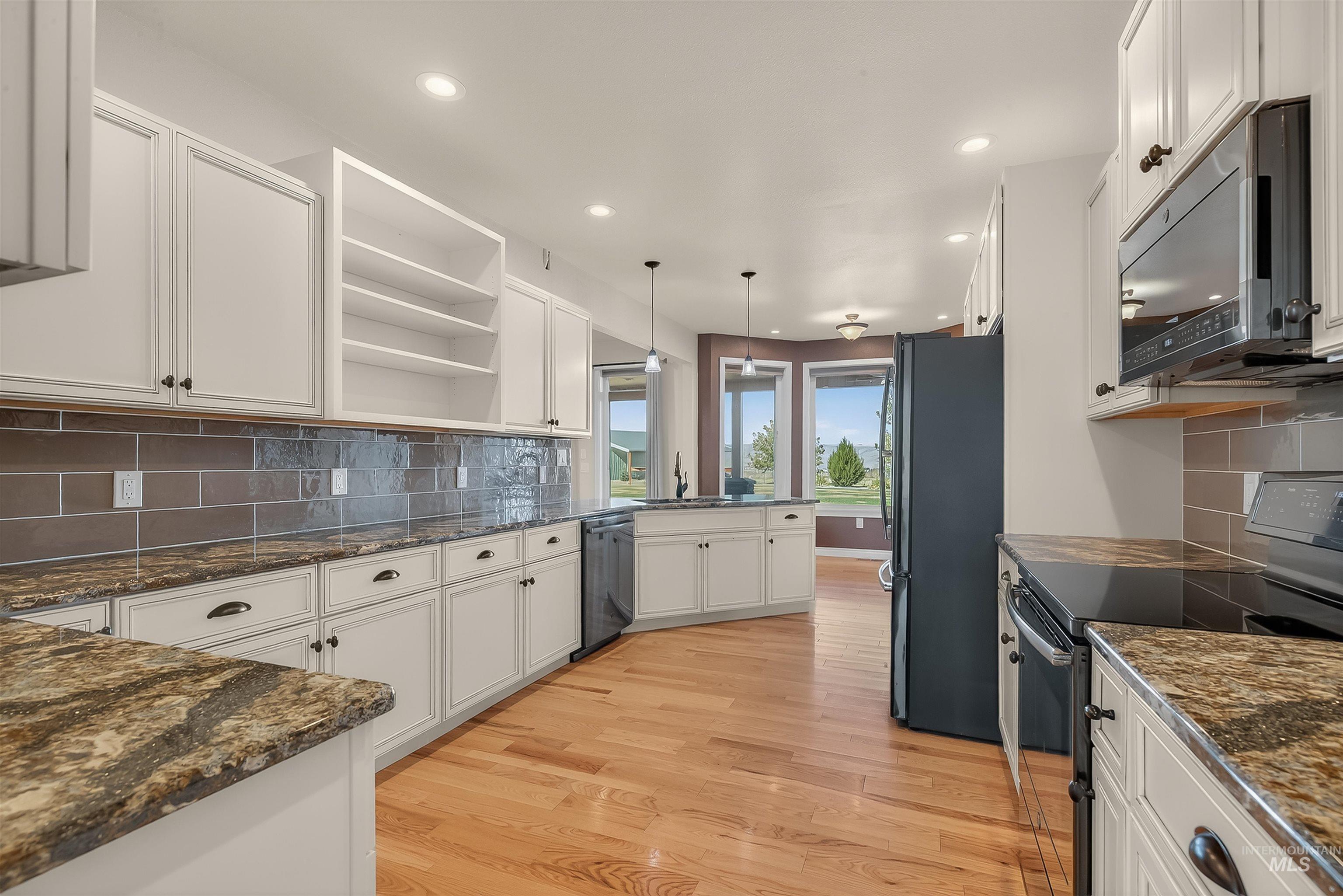 Kitchen with black appliances, open shelves, backsplash, white cabinetry, and decorative light fixtures