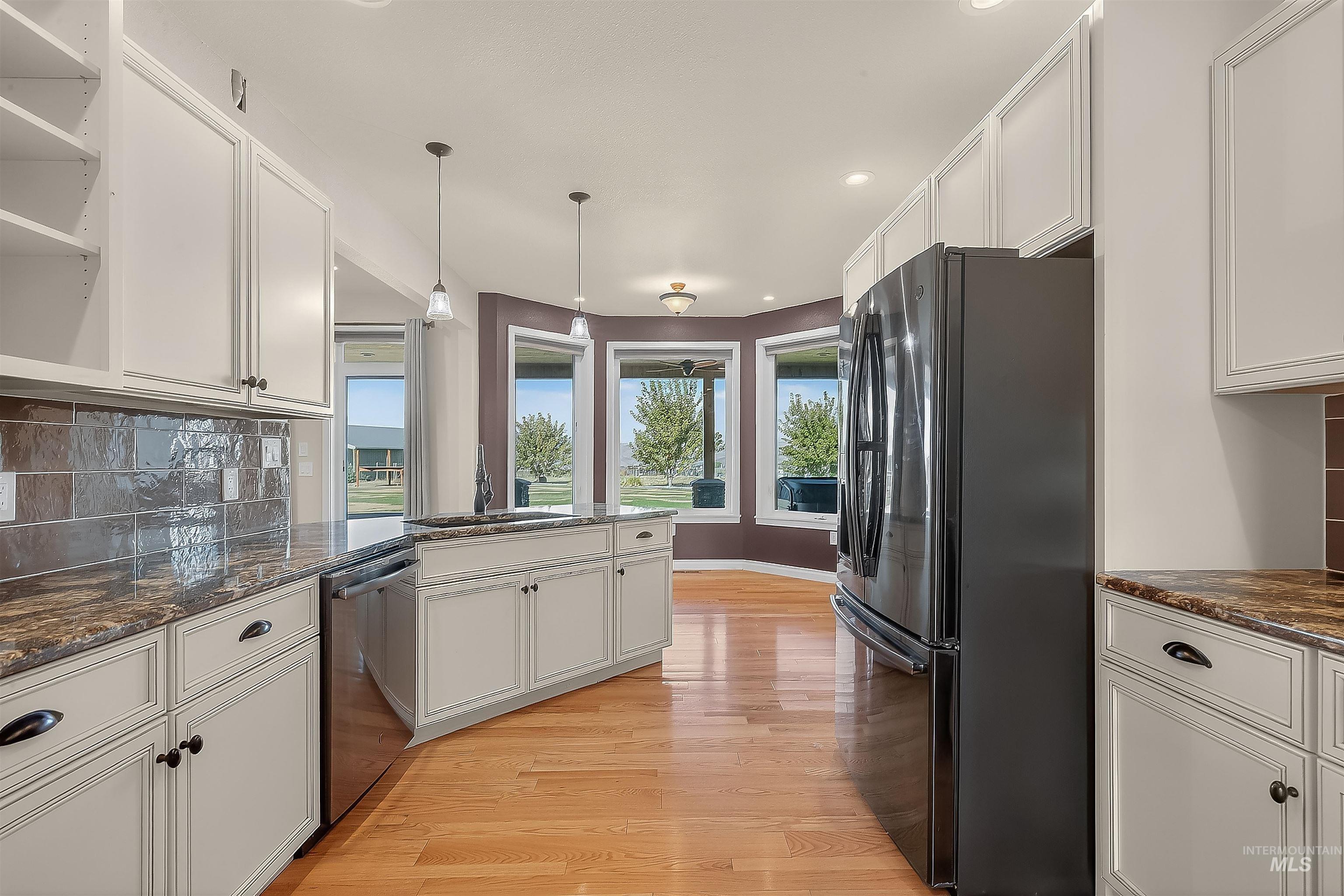 Kitchen with decorative backsplash, freestanding refrigerator, white cabinetry, and recessed lighting