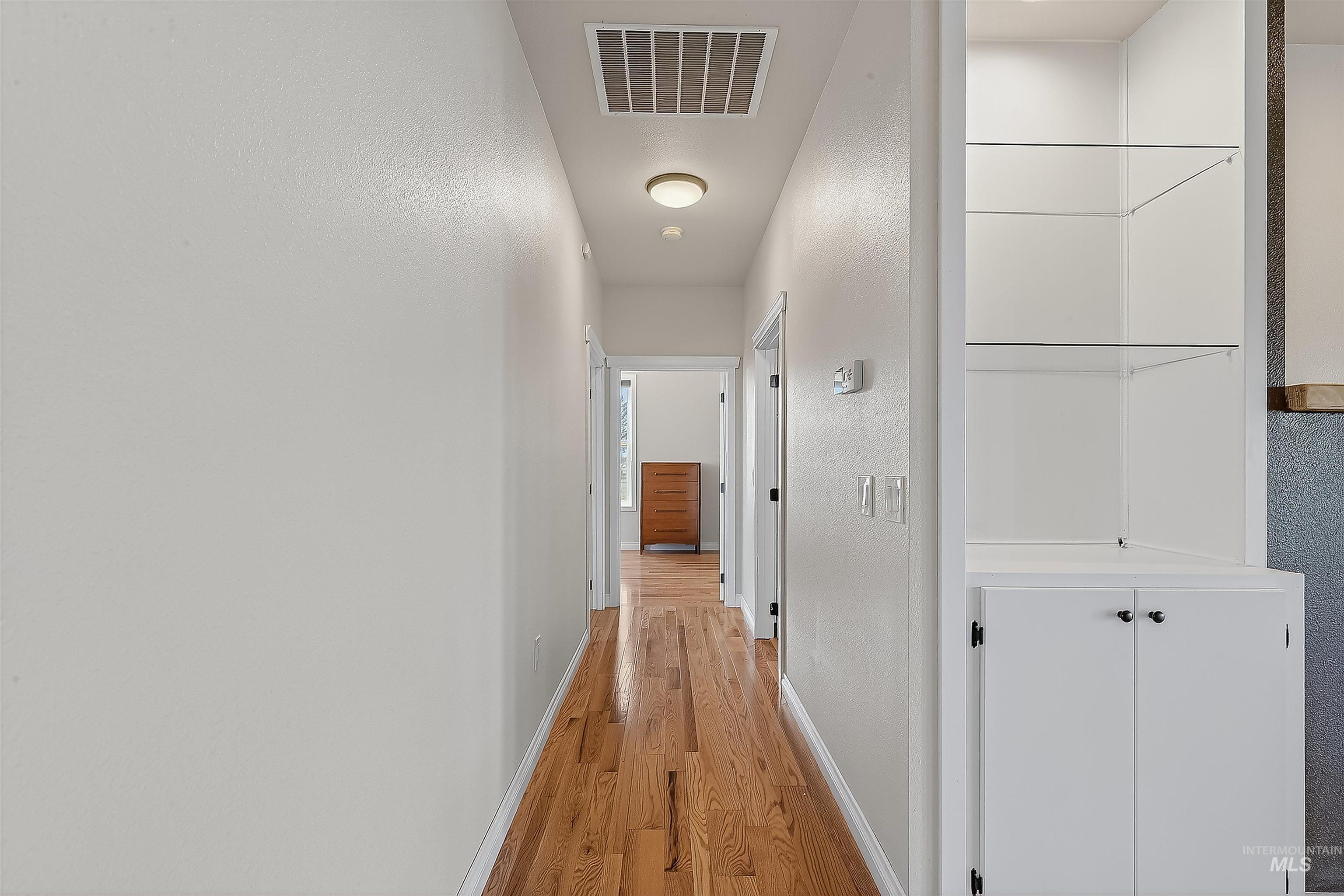 Corridor with light wood-style flooring and a textured wall