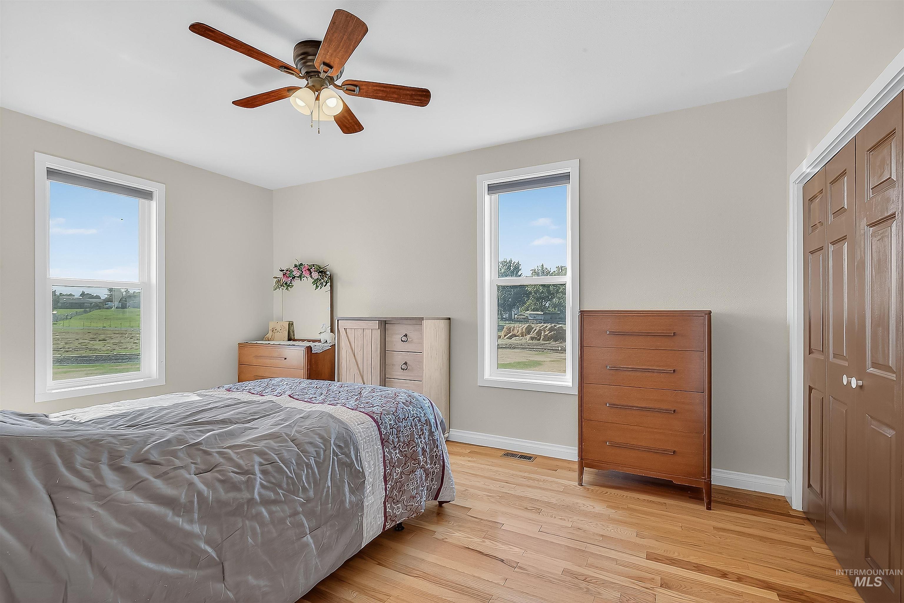 Bedroom featuring light wood-style floors, ceiling fan, and a closet