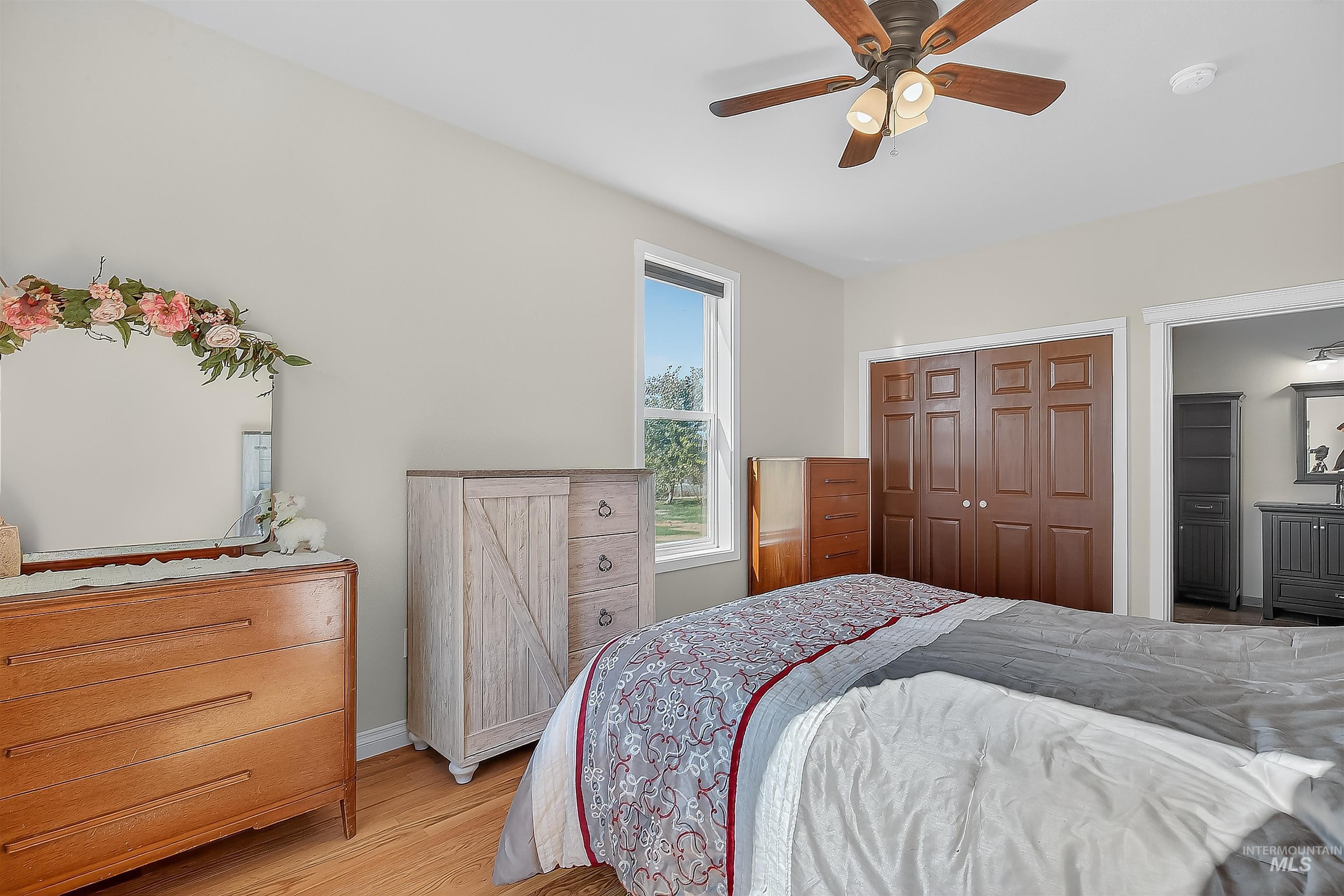 Bedroom with wood finished floors, a ceiling fan, a closet, and connected bathroom