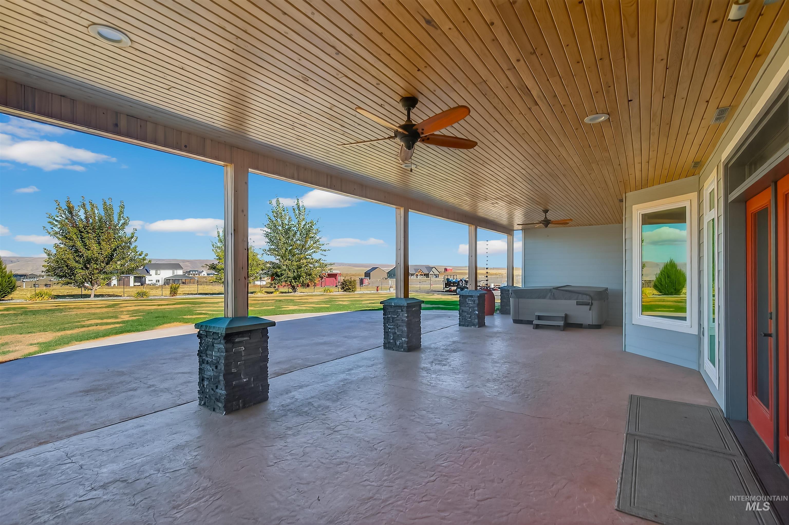 View of patio / terrace with ceiling fan and a hot tub